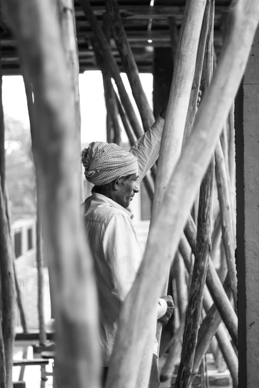 a man standing in front of a building with wood poles