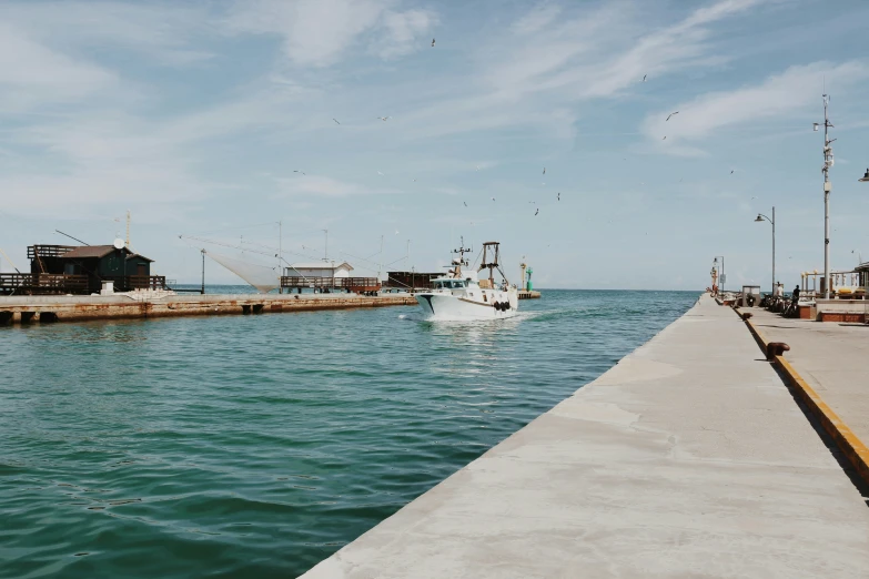 a boat is sitting at the dock while another sailboat passes by