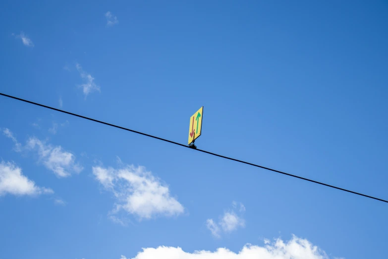 a kite is sitting on a wire and is flying in the sky