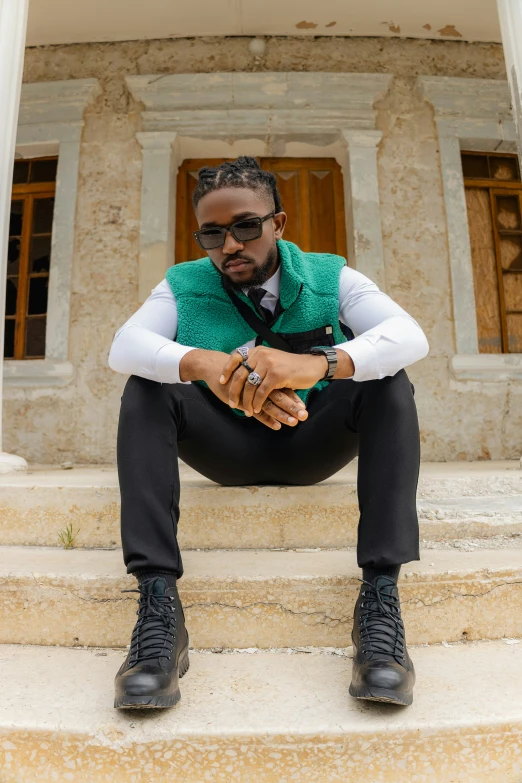 a man in a vest sitting on steps with his legs crossed