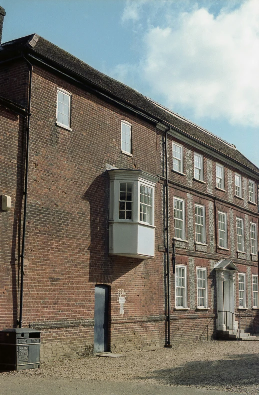 an old building with white windows, blue sky, and a fence in the middle