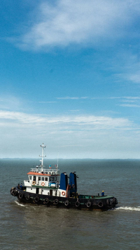 a tug boat traveling on a river with a sky background