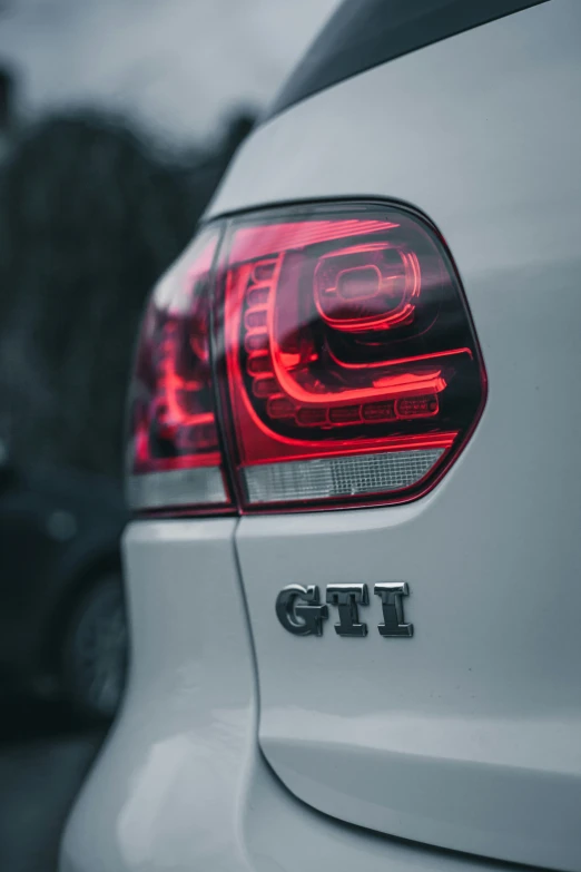 the tail lights of a white car with the gti logo