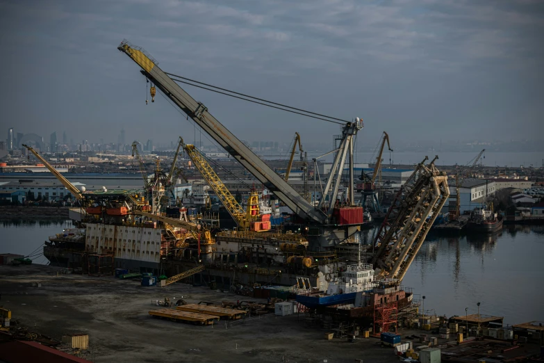 some cranes in a harbor near other boats