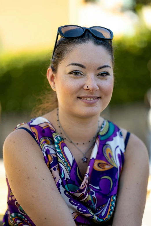 a woman wearing sunglasses sitting outside on a bench