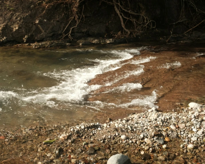 a large river flowing with a pile of stones and sand