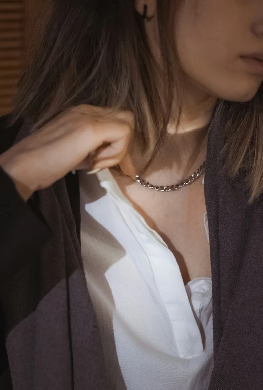 a woman is holding onto her collar while she wears a scarf