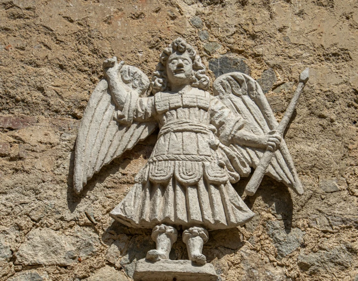 an angel is made of cement on the side of a building