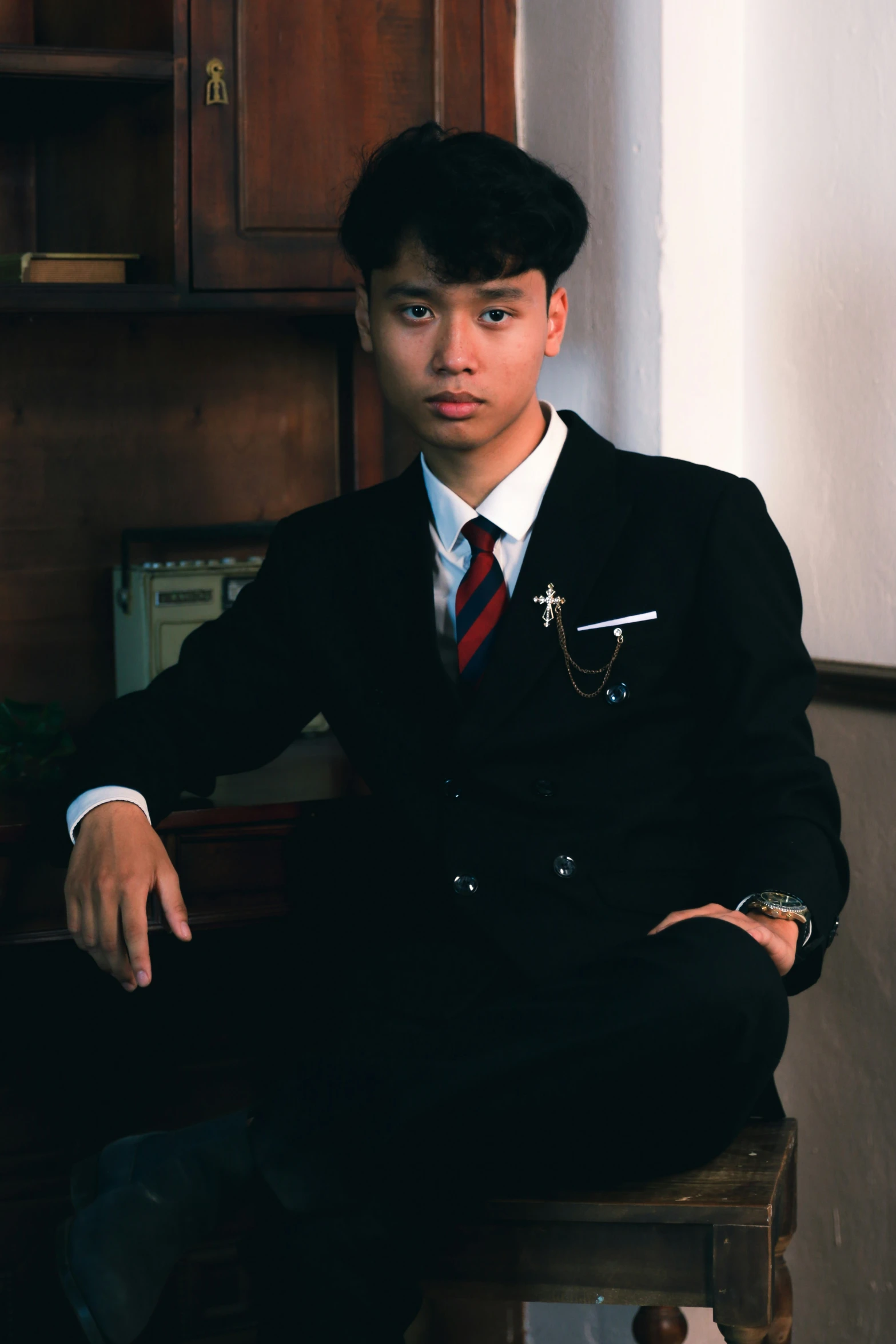 a man in suit and tie sitting on a stool