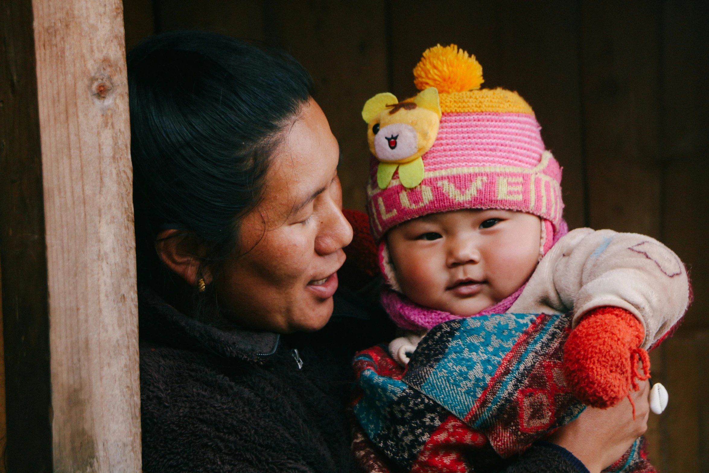 a woman holding a baby wearing a hat and scarf