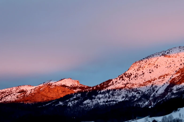 there is a snow covered mountain range at sunset