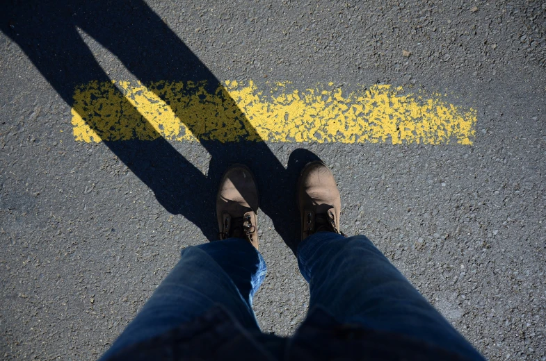 a person with their feet crossed on a yellow arrow