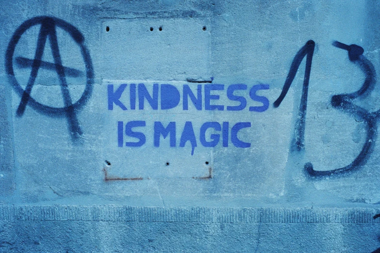 a piece of graffiti on a wall and the word kindness is magic written underneath it