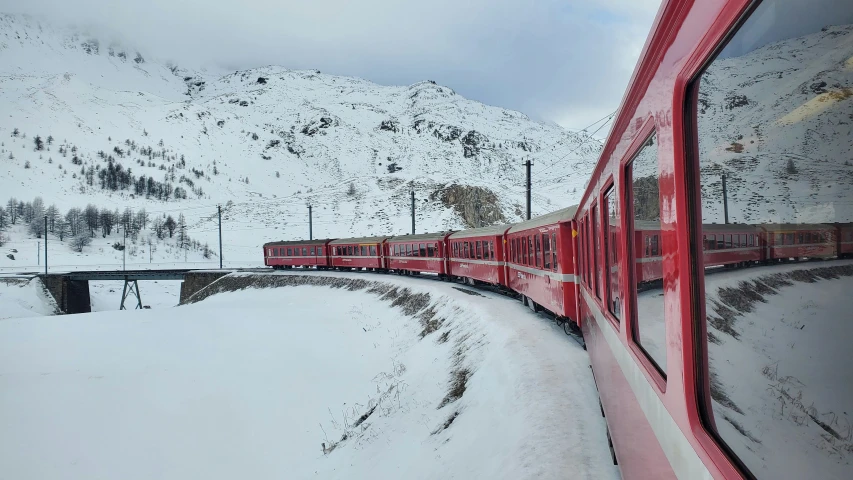 a passenger train on the tracks going through some snow