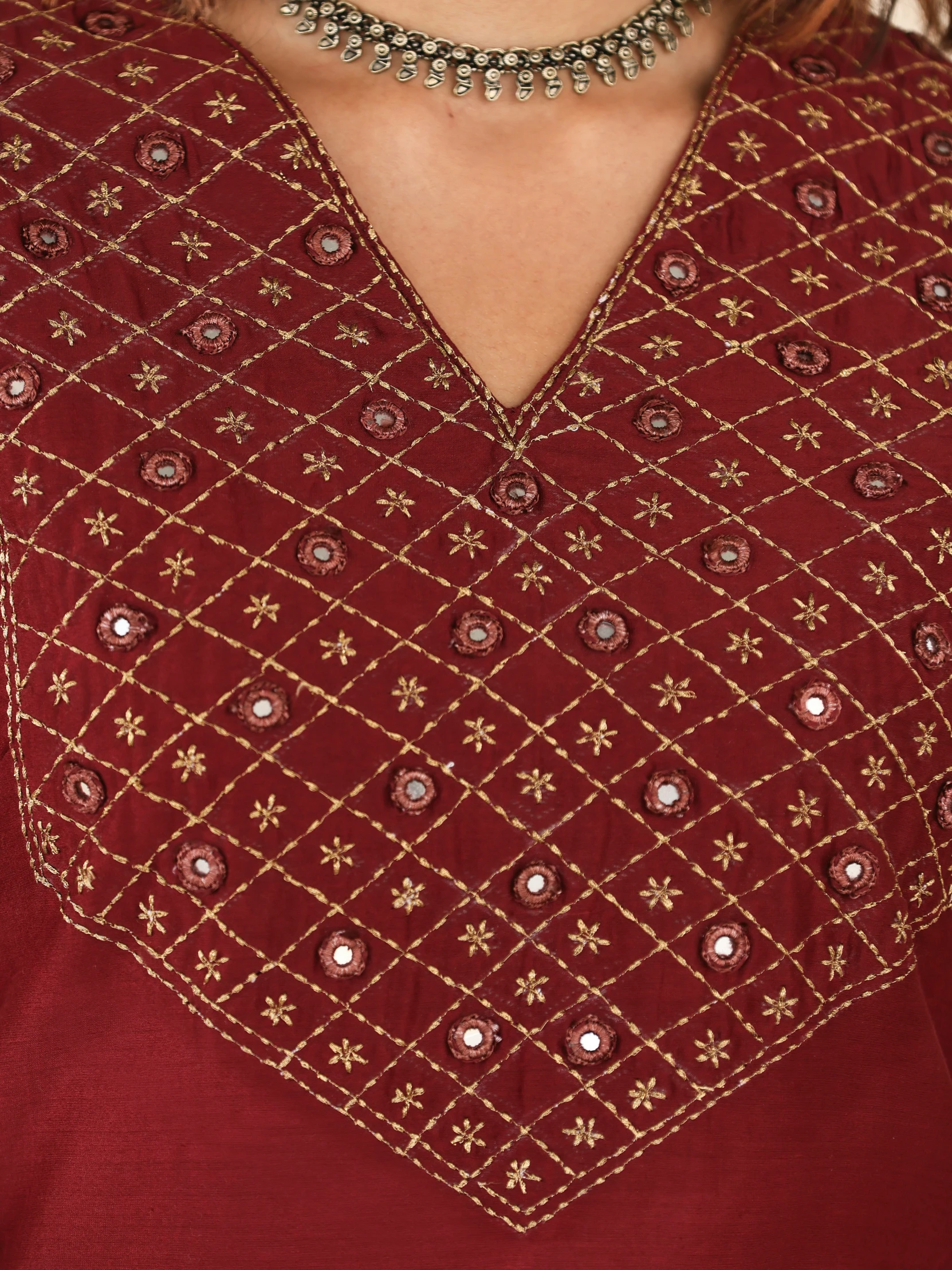 a woman's maroon blouse with gold details