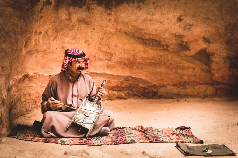 a man sitting on a rug looking at his cell phone