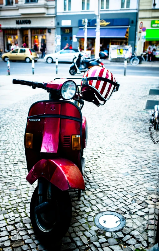 a red motorcycle parked on top of a cobblestone road