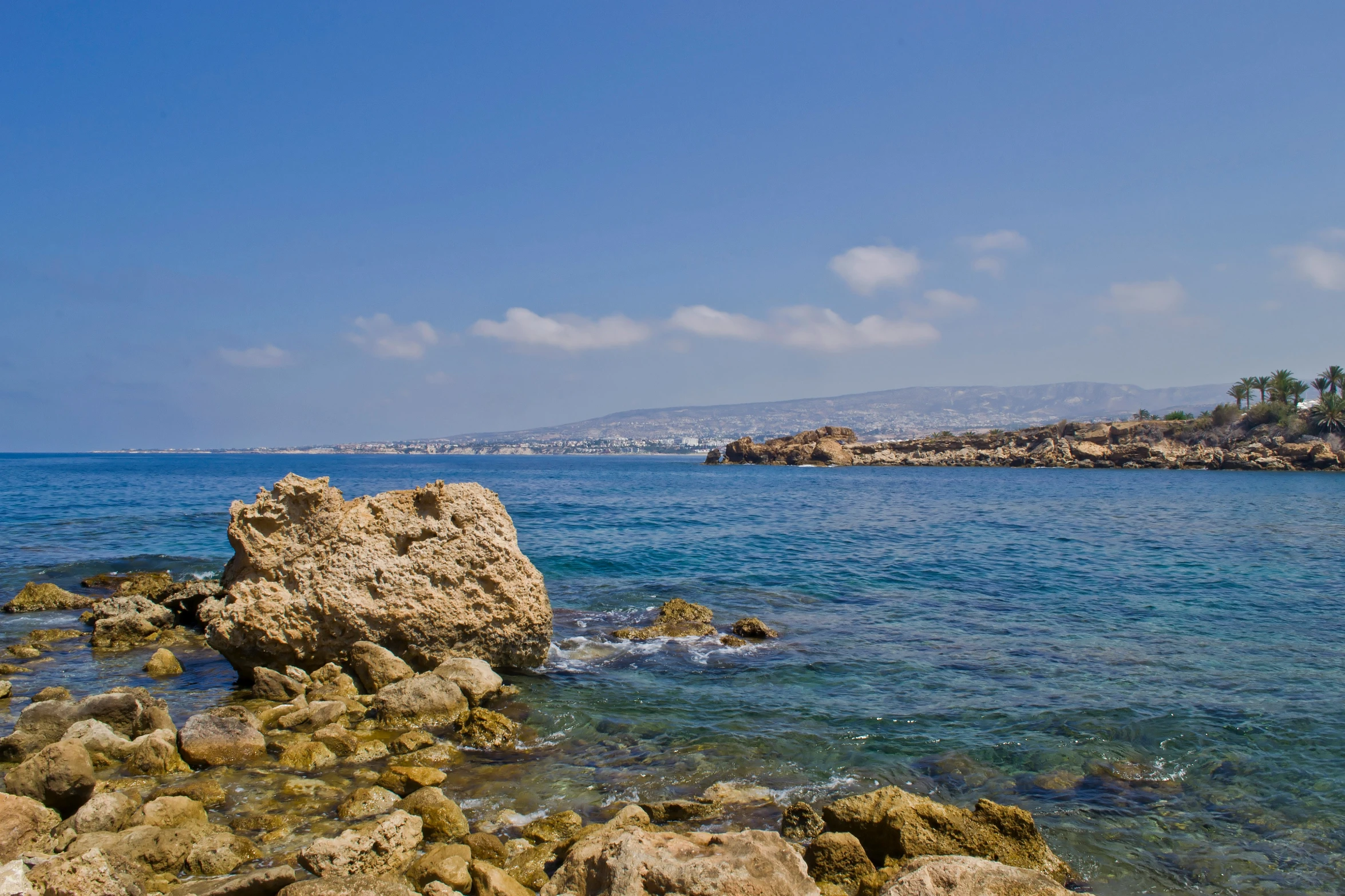 water and rocks near shore with small island in background