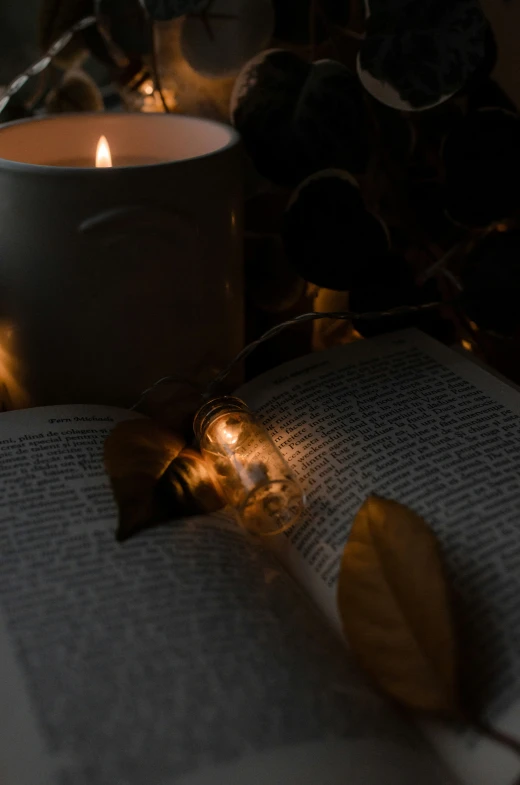 an open book is on the table next to a candle