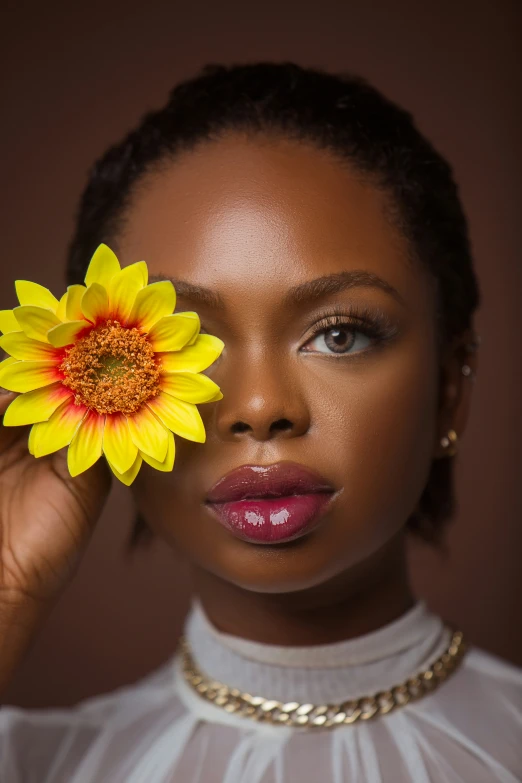 a young woman is holding a flower in front of her face