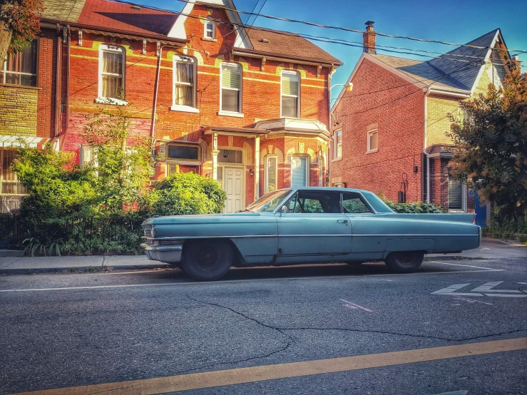 a blue car parked in front of a row of brick houses