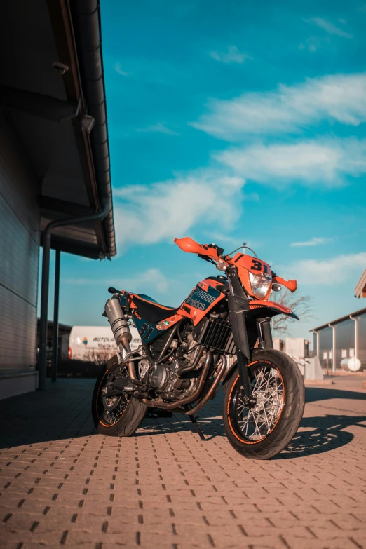 a close up of an orange motorcycle parked near some buildings