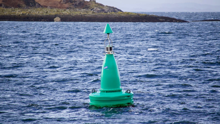 green buoy floating on the surface of blue water