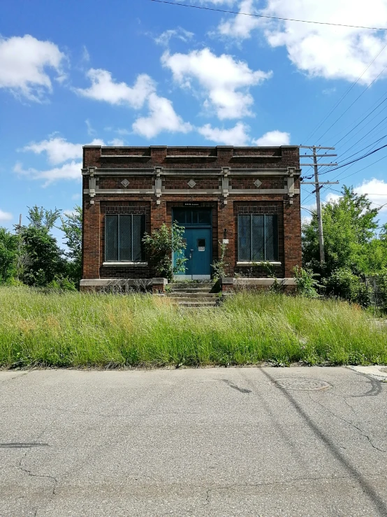 an old brick building with a door next to grass