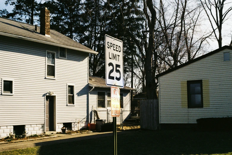 there are two houses one is white and the other has a black and white street sign