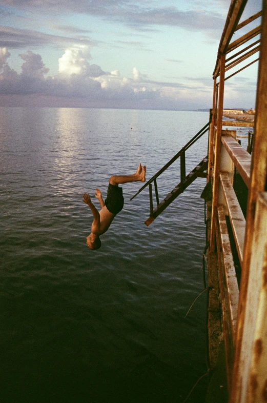 a young man diving off a pier into the water