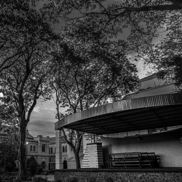 an overhanging building sits behind a tree - lined park