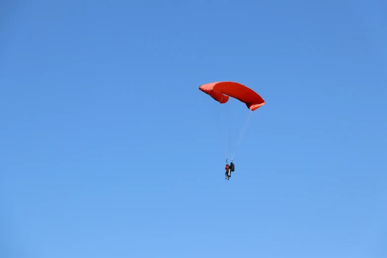 an open parachute is in the sky with a red flag