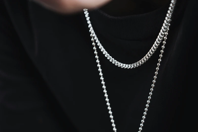 the person wearing a black shirt is wearing three different chains