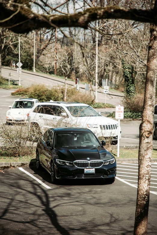 a black bmw parked in a parking space near two cars