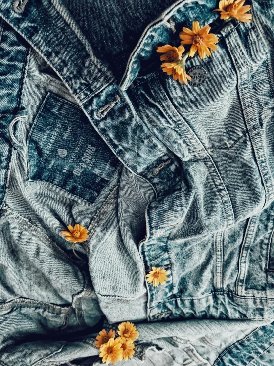 a pair of jeans with yellow flowers lying on them