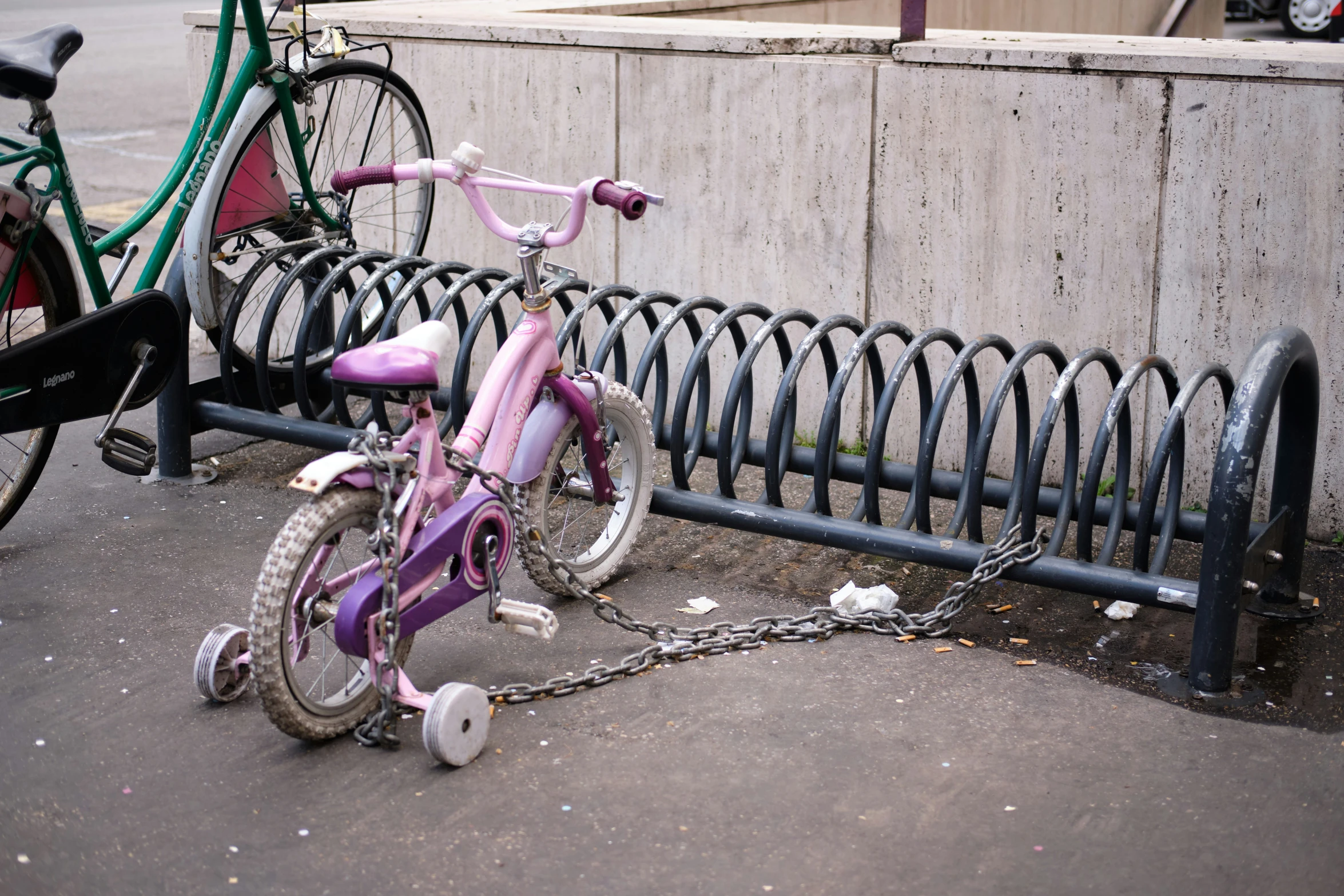 a pink bicycle  to a fence in front of a wall