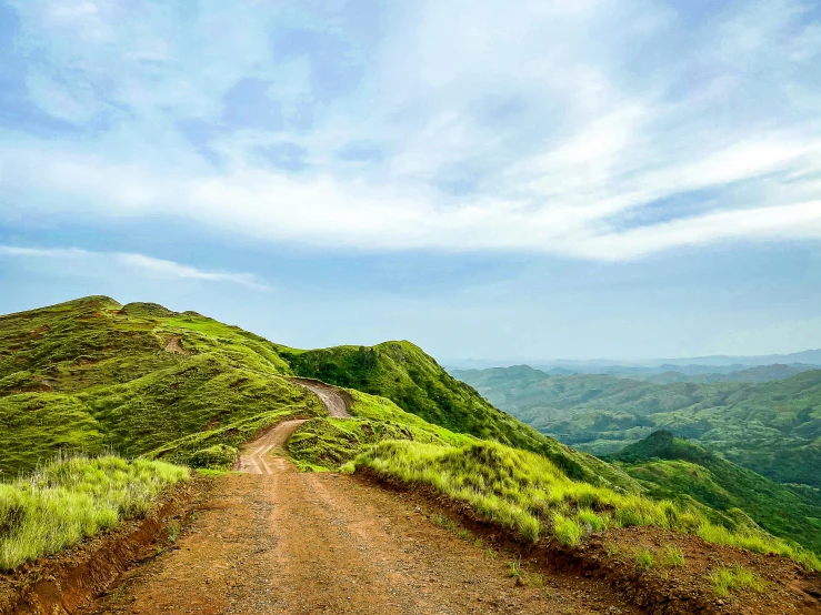 a road going down a hill with green hills in the distance