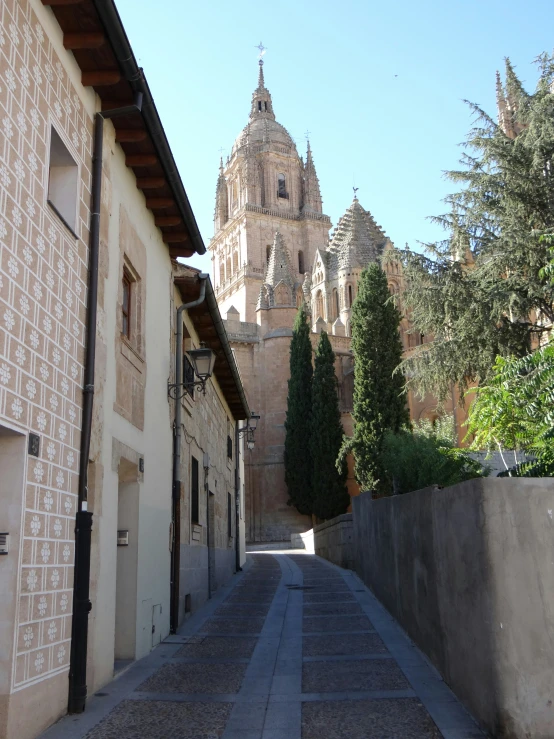 an alley leading to a building with a church steeple in the background