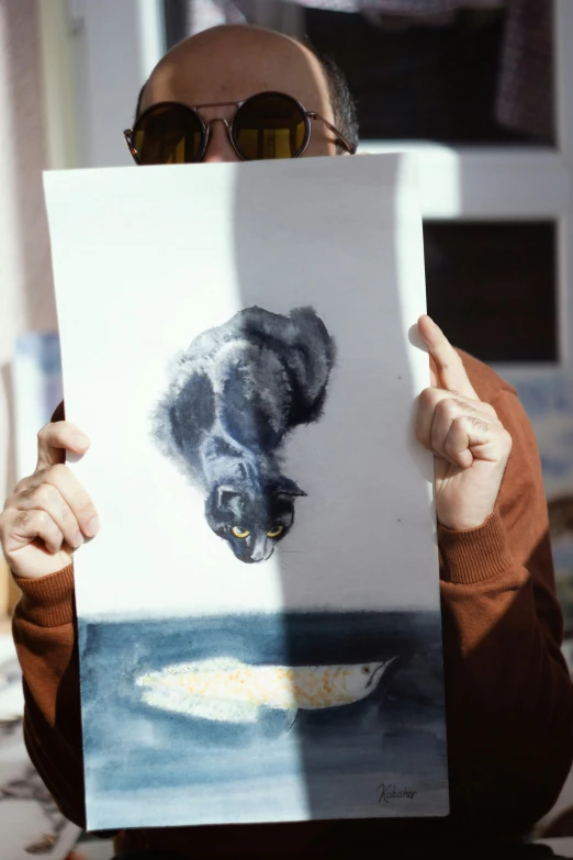 the man is holding up a drawing with a cat