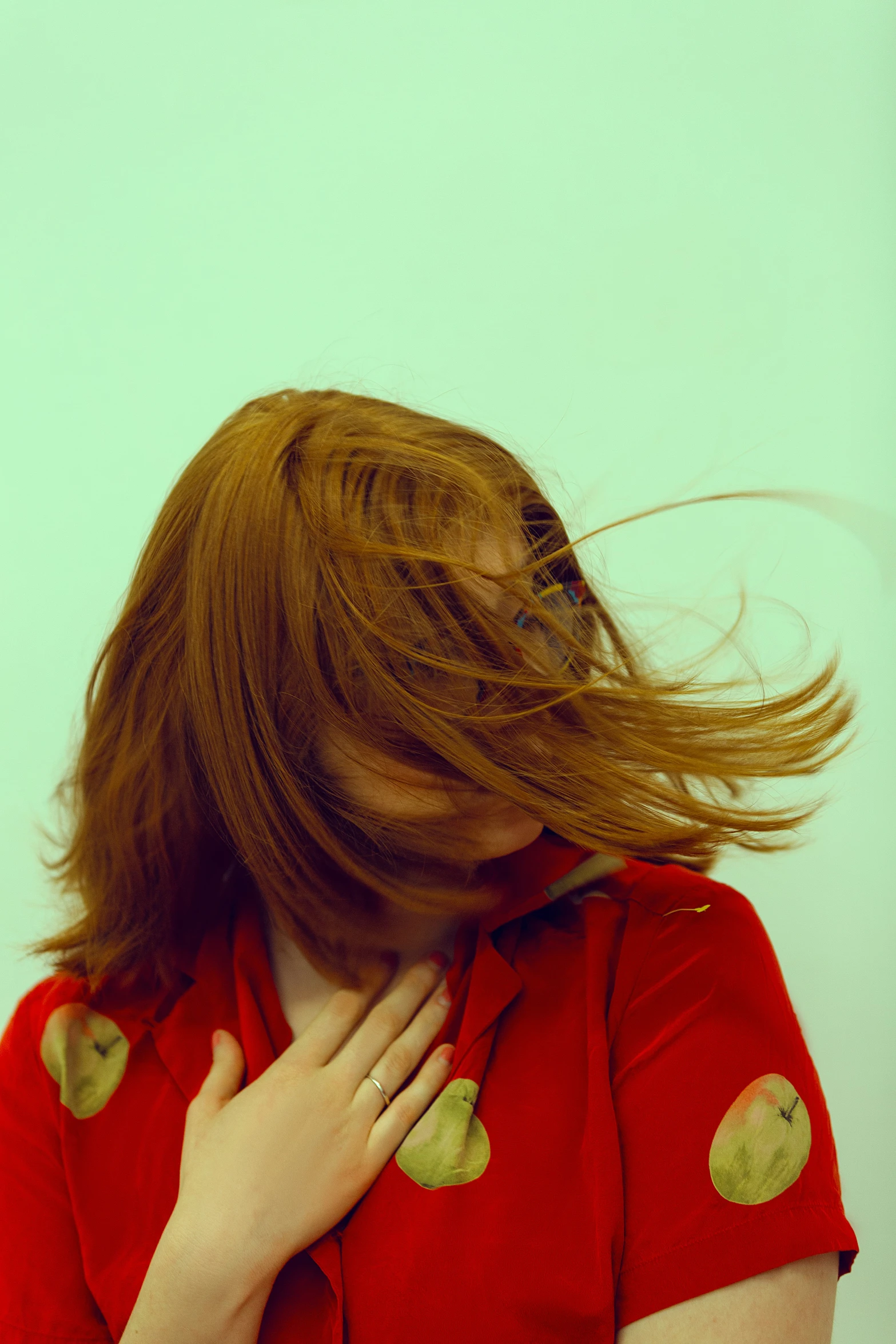 woman in red shirt blowing her hair with green apples on her body