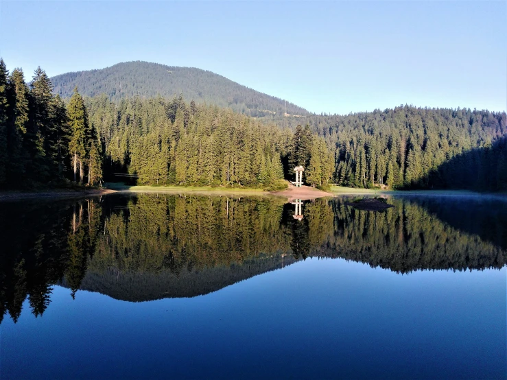 a lake is surrounded by trees and mountains