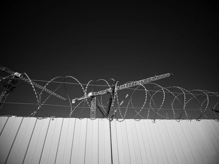 barbed wire along a building wall and with the sky behind