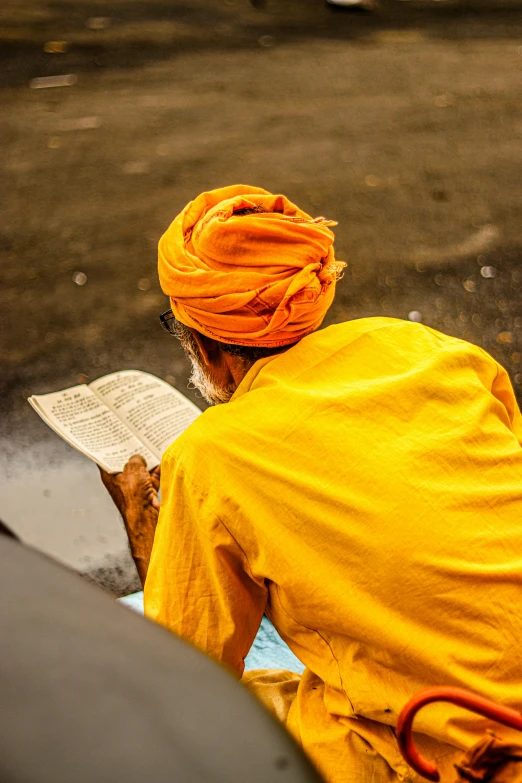 a person in yellow is sitting down reading a book