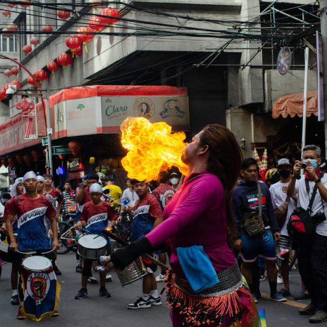 woman holding fireball in street surrounded by band members