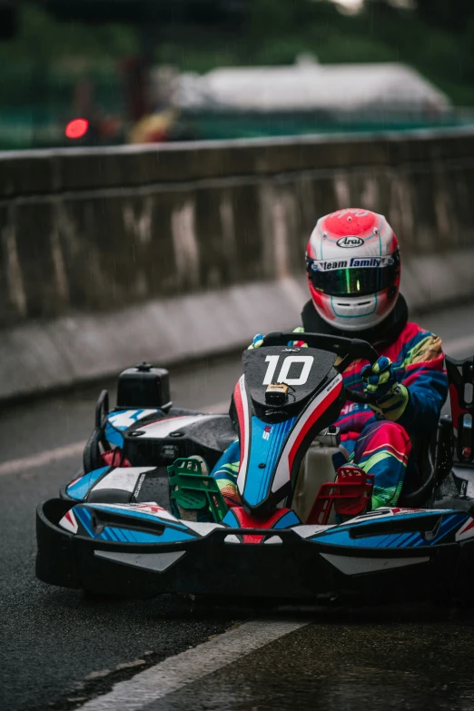 a man in colorful jacket riding an outdoor go - kart