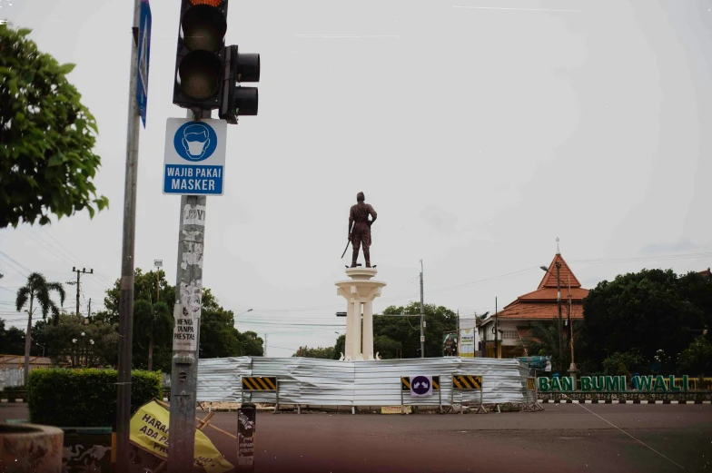 a traffic light with a statue and sign on it