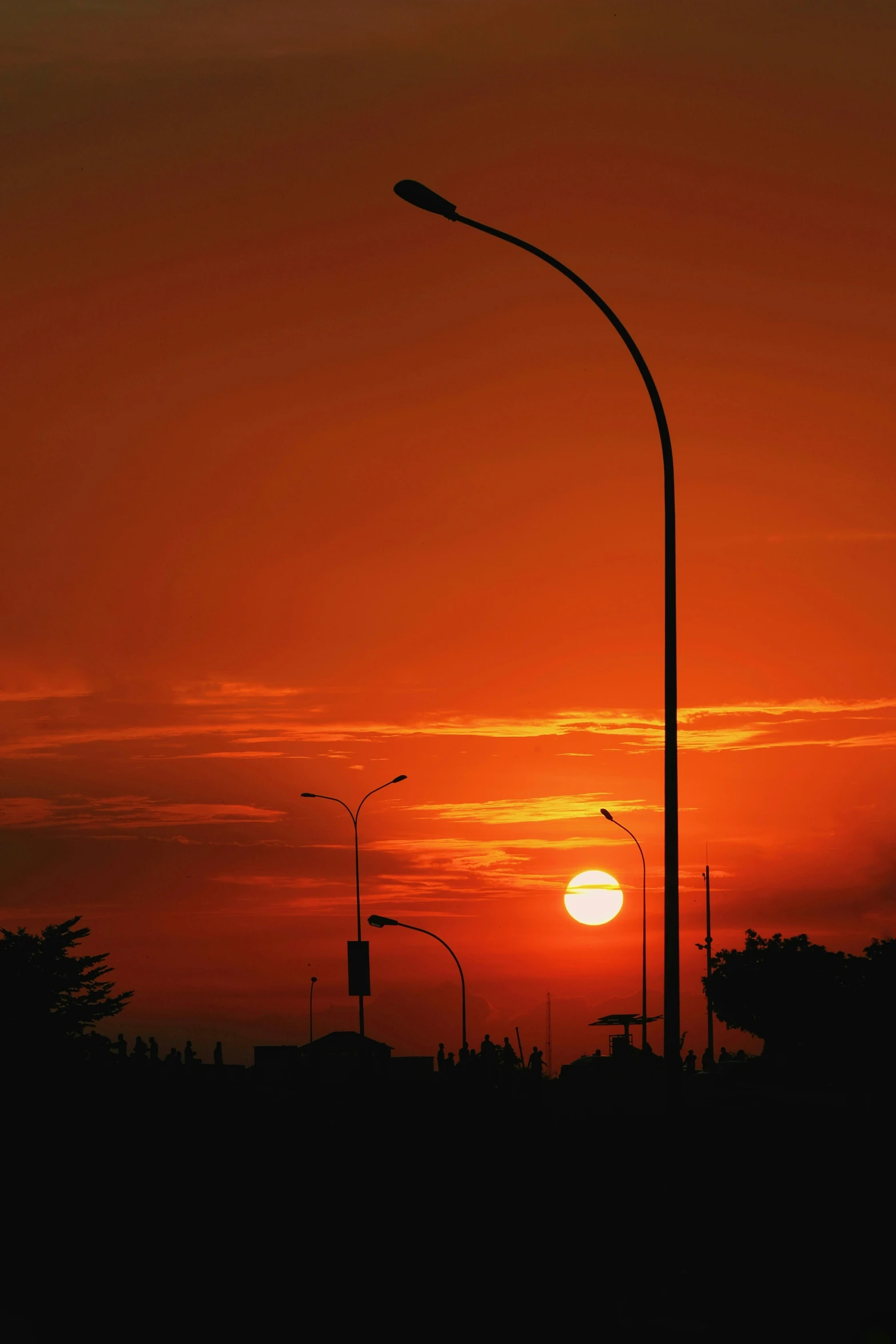 the sun setting in a bright red sky with street lights