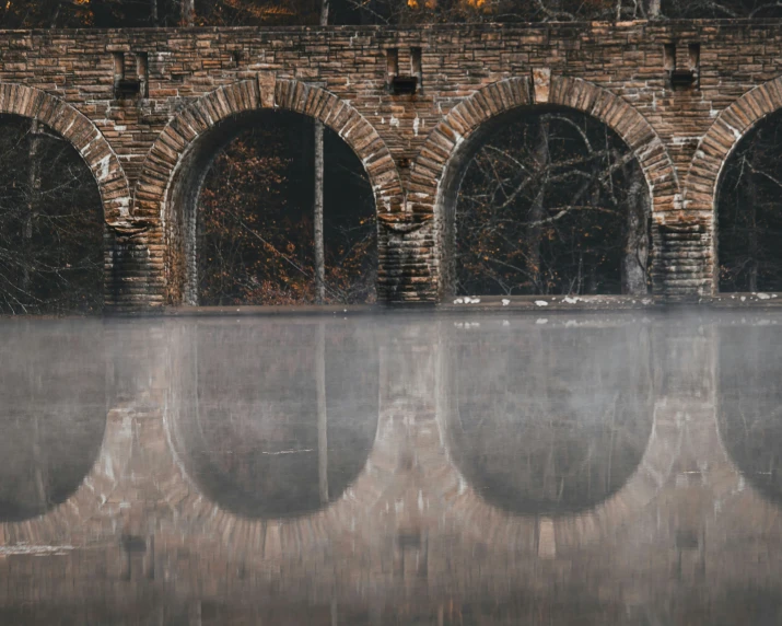 a brick wall reflecting in a still body of water