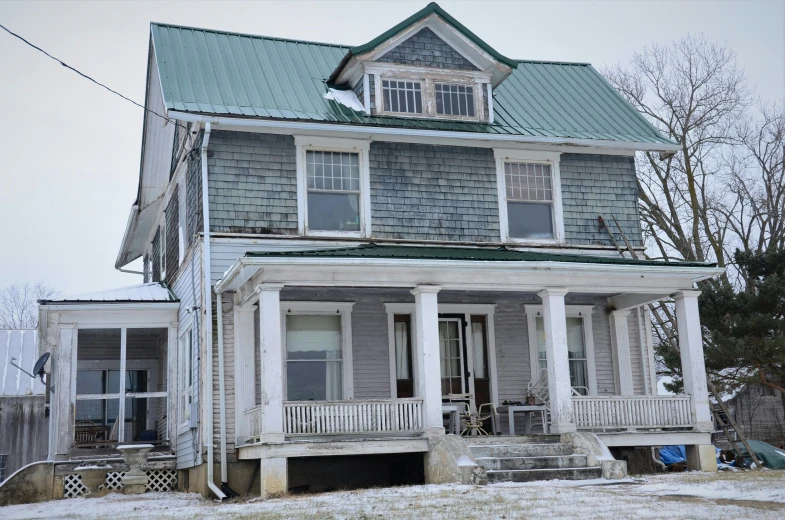 a gray two story house with green roof