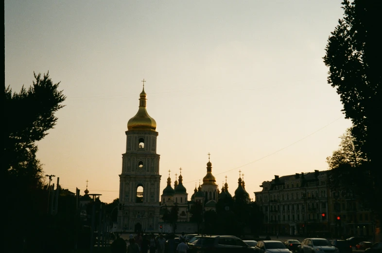 a church tower towering above a large group of parked cars